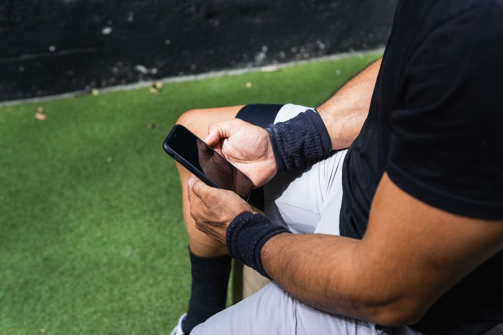 Anonymous fit man browsing smartphone during training
