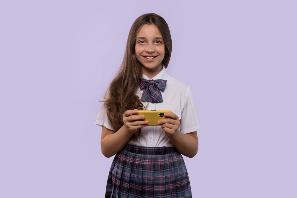 Girl in white shirt and plaid skirt holding smartphone