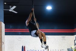 Strong sportsman exercising on climbing rope