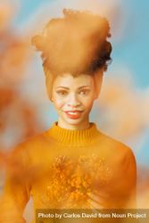 Studio shoot of Black woman holding orange flowers behind orange cloud effect 42jZ14