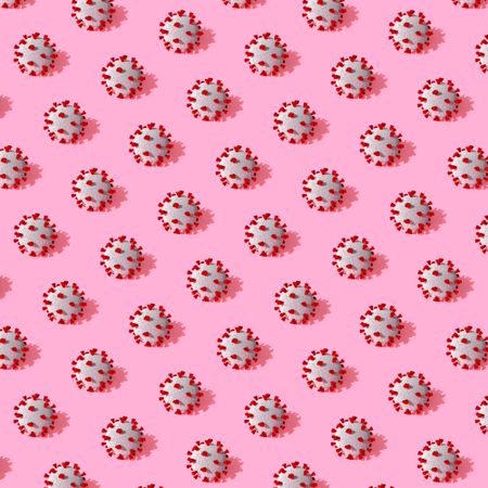COVID-19 virus pattern in rows on pink background