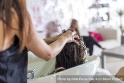 Woman having her hair rinsed in sink at salon 0V3d35