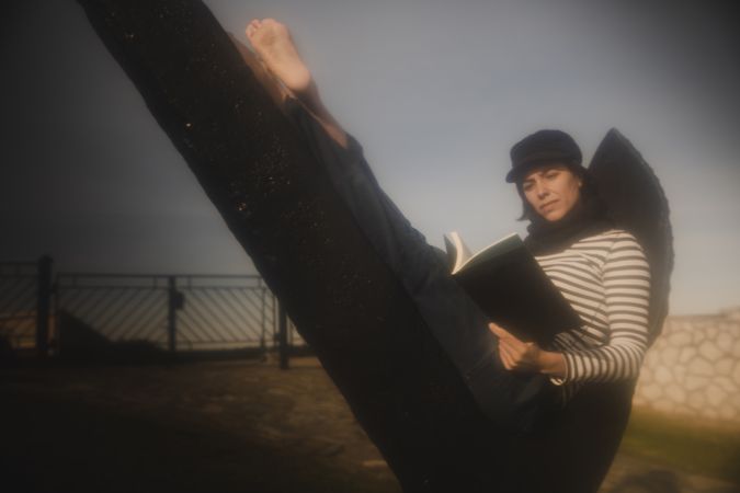Woman with book sitting on monument near building on shore