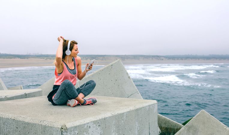 Sportswoman with headphones sitting and dancing