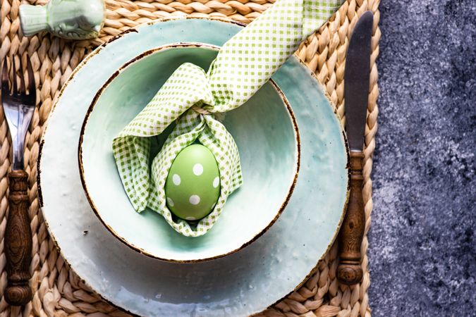 Top view of Easter holiday table setting with pastel egg wrapped in napkin