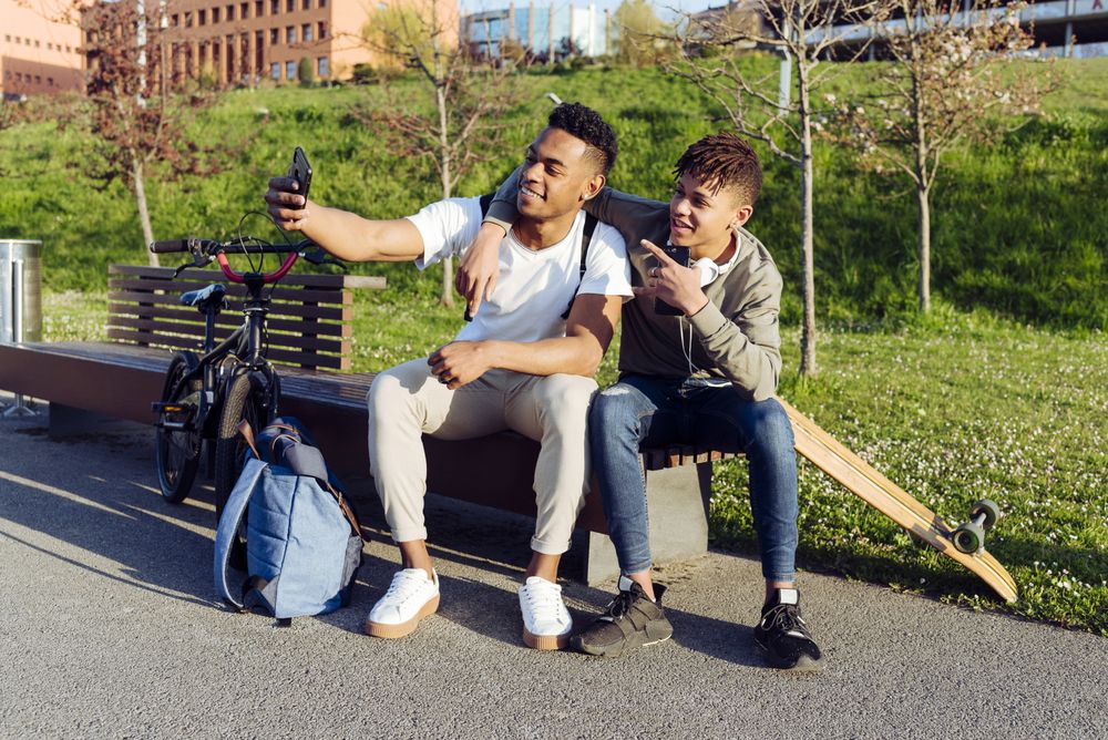 Young Black men sitting on bench with smartphone