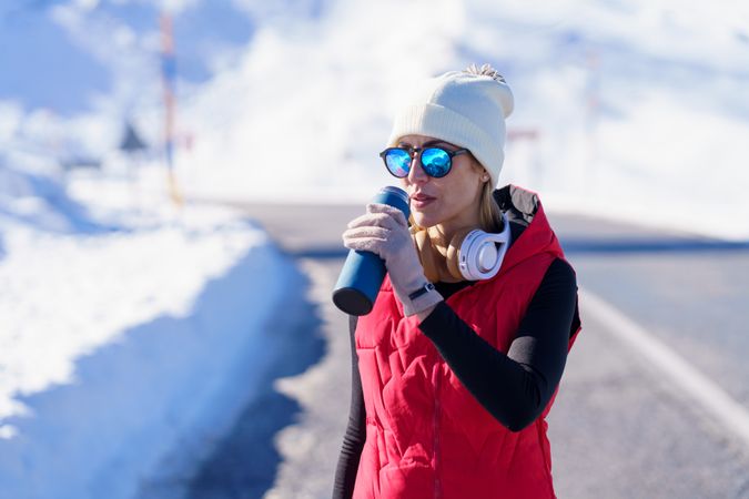 Woman in wintry gear sipping from bottle in the mountains on cold day