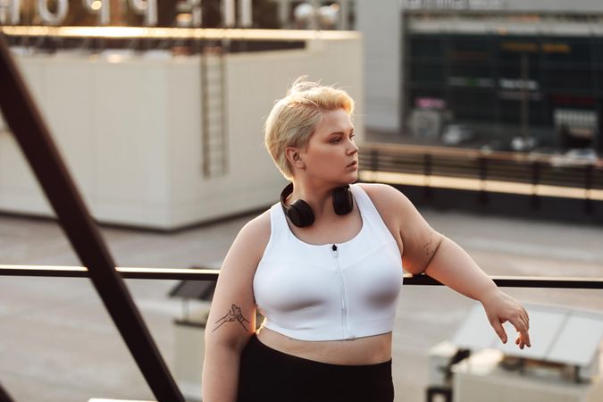 Female model leaning to a railing during a workout on a roof