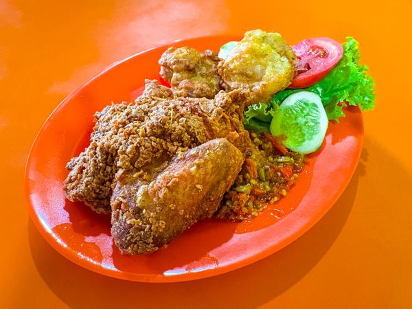 Ayam Geprek with Fried Tofu and Vegetables on Orange Plate