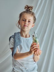 Serious boy holding glass bottle and looking at camera