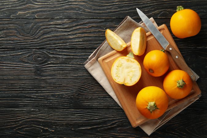 Board with zucchini, knife and towel on wooden background
