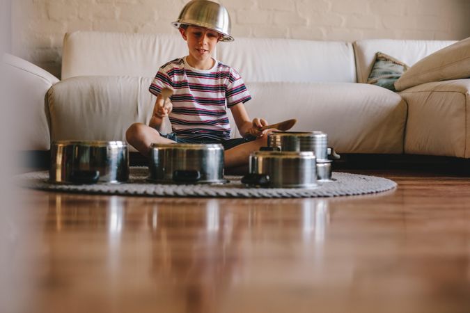 Little musician playing drums on kitchenware at home