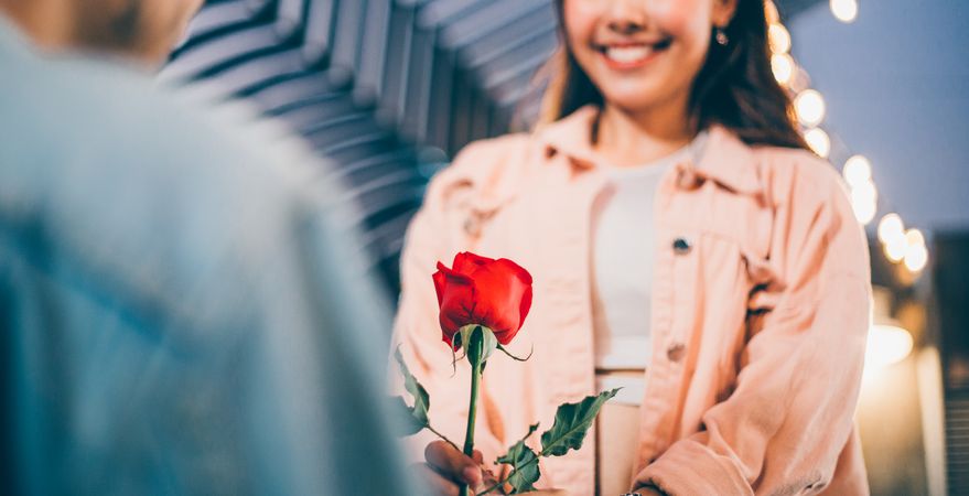 Smiling woman happy and receiving a surprise rose from boyfriend