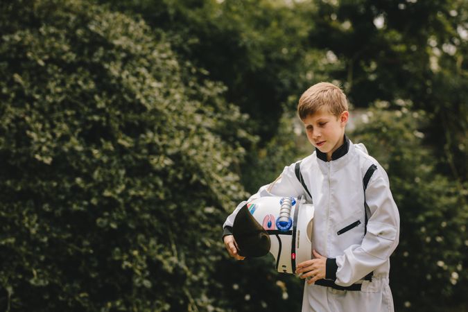 Boy wearing space suit holding a helmet walking outdoors
