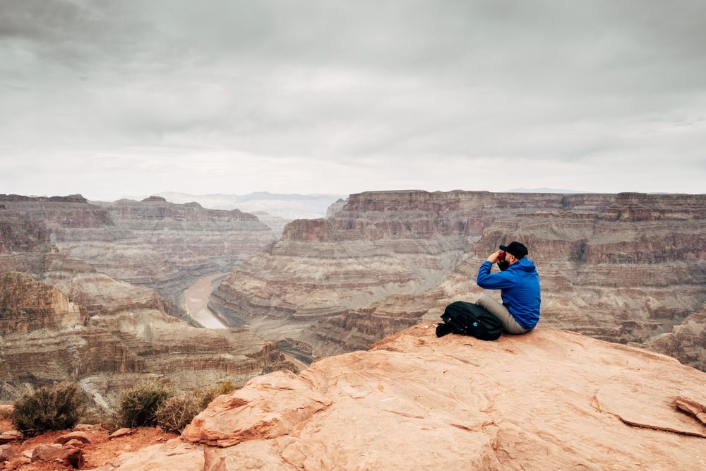 Male relaxing on cliff and admiring picturesque view