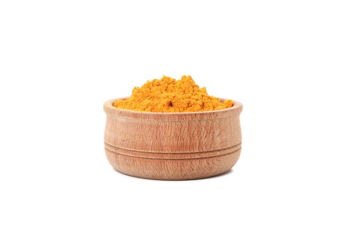 Side view of bowl of loose turmeric powder