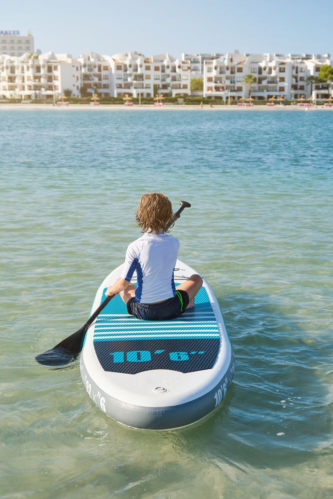 Anonymous boy floating on paddleboard in ocean