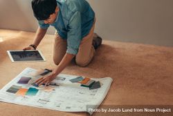 Man holding digital tablet on floor with housing plan and color swatches 5XPGV5