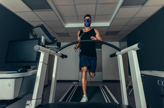 Fit young man running fast on treadmill with a mask for VO2 max test
