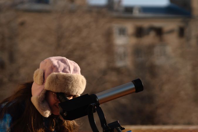 Girl in colorful jacket points while preparing solar telescope observation