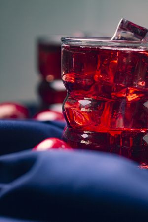 Red beverage near fresh fruits on cloth