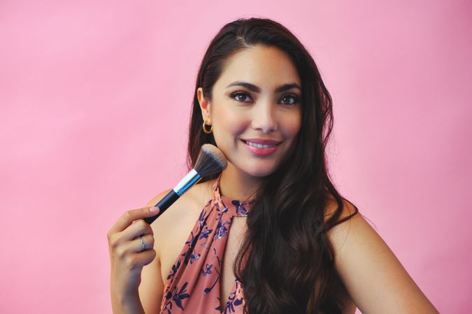 Head shot of elegant Hispanic woman holding large make up brush
