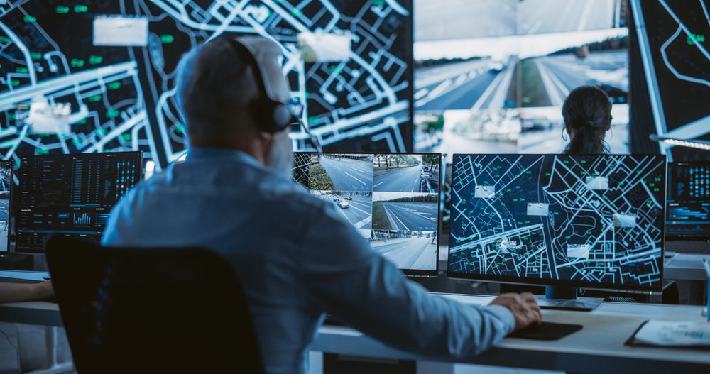 Specialist in a Dark High-Tech Monitoring Room, Concentrated on a Call and Computer Work.