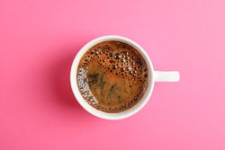 Cup of coffee on color background, space for text