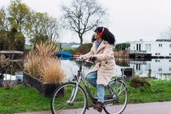 Excited Black woman in headphones riding bicycle