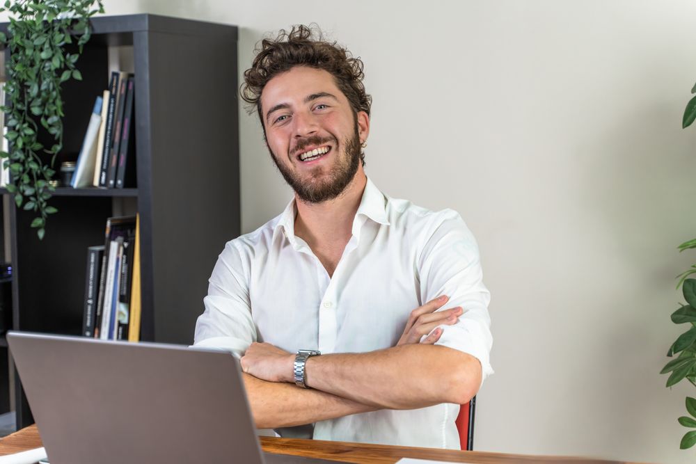Confident young businessman smiling at the camera in his office.