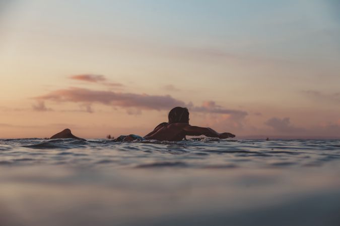 Man on surf board on waving water at sunset