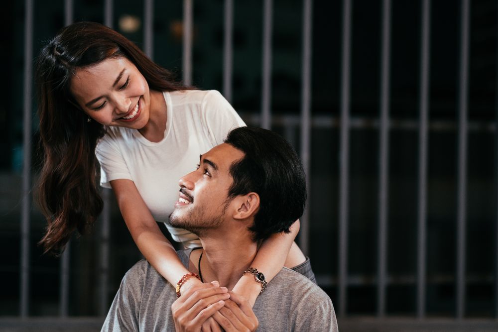 Woman embraces man's shoulder and looking into his eyes