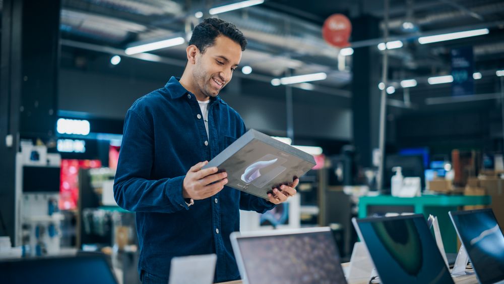 Young Man Shopping for a Tablet in a Home Electronics Store.
