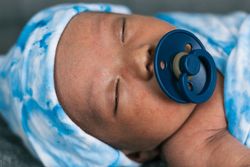 Newborn baby wrapped on soft blanket with pacifier