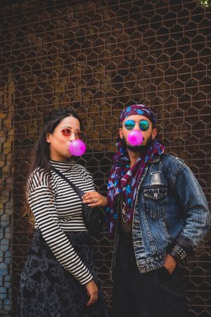 Man and woman wearing sunglasses blowing purple bubble gum