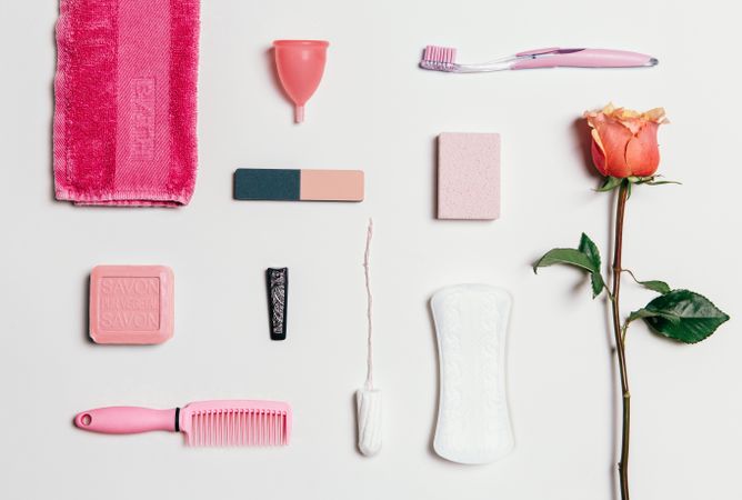 Feminine accessories in pink tones over plain background