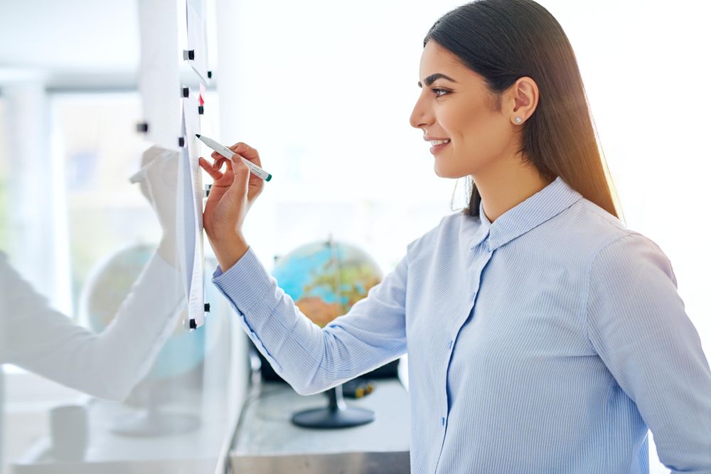 Calm female entrepreneur working off a dry erase board in bright office