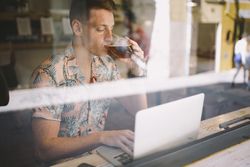 Man talking on smartphone while browsing laptop