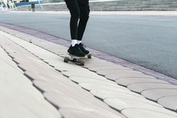 Unrecognizable woman rides on longboard around sunlit park