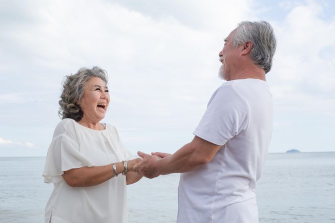 Older Asian couple facing each other at the beach
