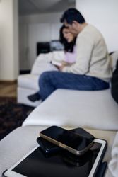 Digital Detox: Phones Foreground with Blurred Couple Reading Book in Background