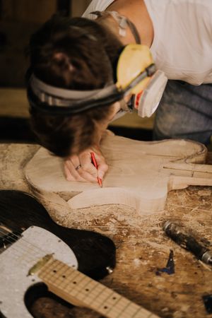 Cropped image of young person making an electric guitar from wood