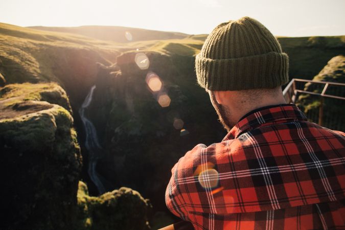 Back of man looking over green cliffs