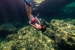 Anonymous boy diving on seawater with reefs