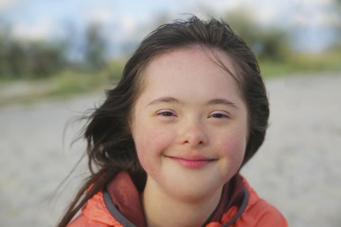 Close up portrait of happy little girl with Down syndrome and blurred background