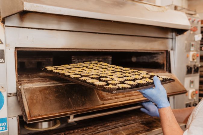 Unrecognizable confectioner putting pastry in oven