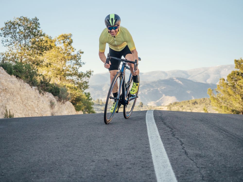 healthy man riding a bicycle on a mountain road in a sunny day