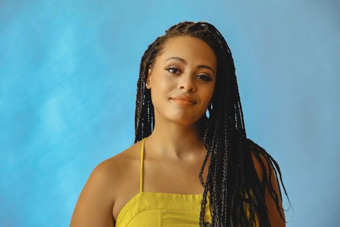 Portrait of bemused female with long braided hair in yellow shirt