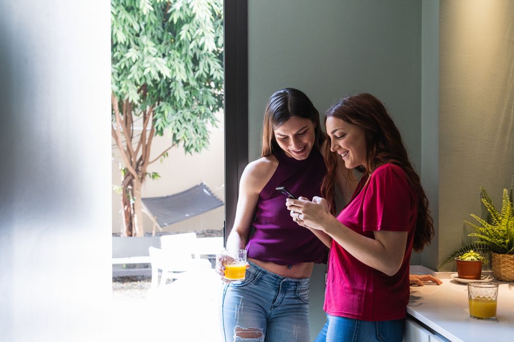 Content women browsing smartphone and enjoying orange juice