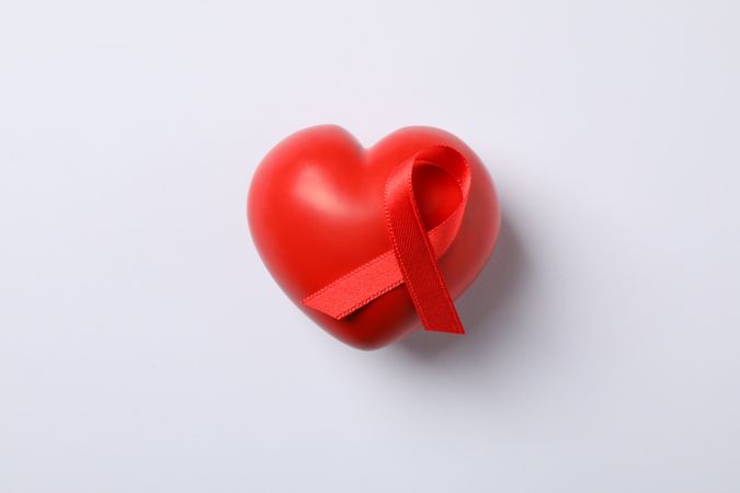 AIDS awareness red ribbon and heart on blank background, space for text